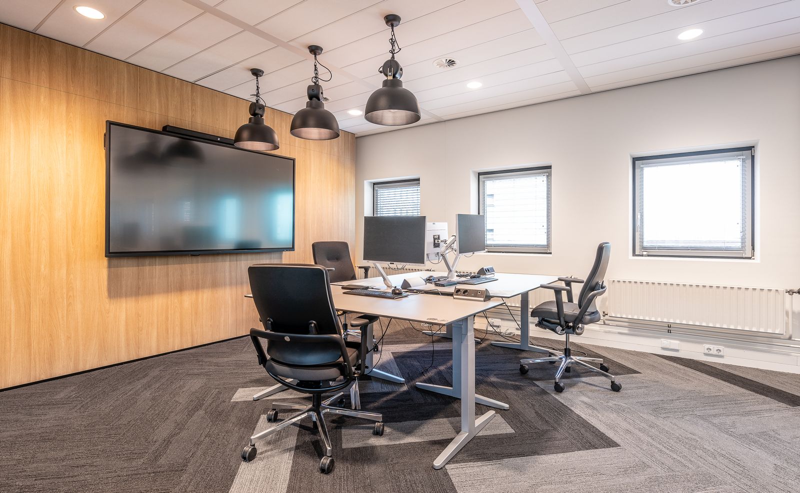 An empty executive office with a large wall-mounted display screen